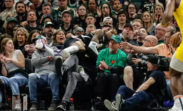 Milwaukee Bucks' Kevin Porter Jr. leaps into the crowd trying to save a ball against the Indiana Pacers during the first half of Game 4 of a first-round NBA basketball playoff series Sunday, April 27, 2025, in Milwaukee. (AP Photo/Jeffrey Phelps)