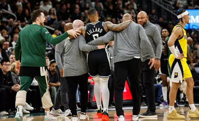 Milwaukee Bucks' Damian Lillard is helped from the floor against the Indiana Pacers during the first half of Game 4 of a first-round NBA basketball playoff series Sunday, April 27, 2025, in Milwaukee. (AP Photo/Jeffrey Phelps)