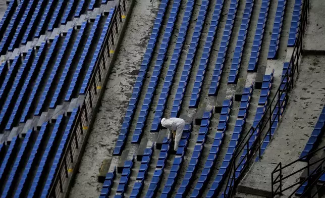 A worker cleans the seats at the San Siro Stadium where the opening ceremony for at the Milan Cortina 2026 Winter Olympics will take place, in Milan, Italy, Monday, Jan. 27, 2025. (AP Photo/Luca Bruno)