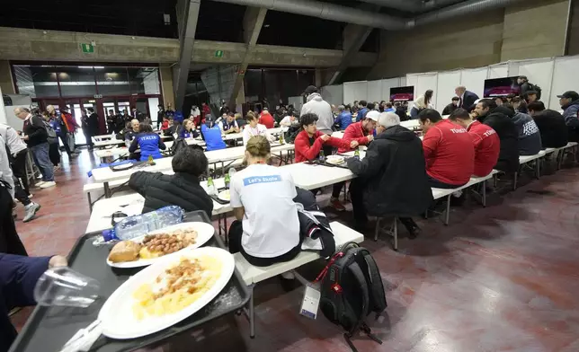 Athletes eats in the backstage prior to compete during the ISU Short Track World Tour and Olympics Milano-Cortina 2026 test event at the the Assago Forum, in Assago near Milan, which will be the Milano Ice Skating Arena where figure skating and short track speed skating disciplines of the Milan Cortina 2026 Winter Olympics will take place, Saturday, Feb. 15, 2025. (AP Photo/Luca Bruno)
