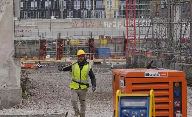 A worker walks inside the construction site of the Olympic Village for the Milan Cortina 2026 Winter Olympics, at the Porta Romana former railway yard, in Milan, Italy, Wednesday, March 1, 2023. (AP Photo/Luca Bruno)