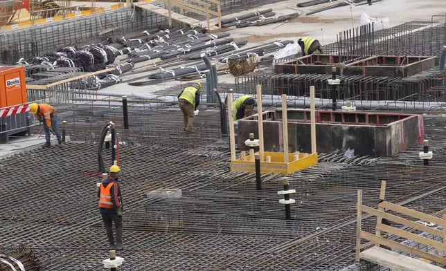 Workers operate inside the construction site of the Olympic Village for the Milan Cortina 2026 Winter Olympics, at the Porta Romana former railway yard, in Milan, Italy, Wednesday, March 1, 2023. (AP Photo/Luca Bruno)