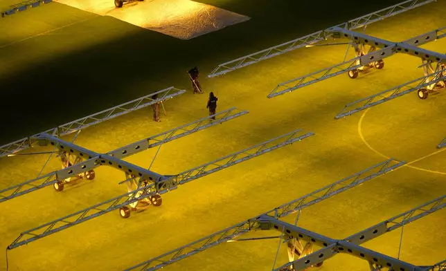 Workers tend to the grass at the San Siro Stadium where the opening ceremony for at the Milan Cortina 2026 Winter Olympics will take place, in Milan, Italy, Monday, Jan. 27, 2025. (AP Photo/Luca Bruno)