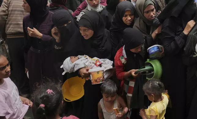 Palestinians wait for donated food at a distribution center in Nuseirat, central Gaza Strip, Wednesday, April 30, 2025. (AP Photo/Abdel Kareem Hana)