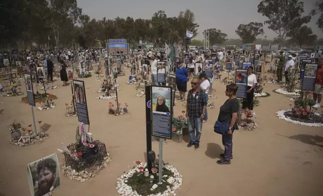 People stand still to observe two minutes of silence as air raid sirens sound marking the Israel's annual Memorial Day at the site of Oct. 7, 2023 attack by Hamas militants at the Nova music festival near Kibbutz Reim, southern Israel, Wednesday, April 30, 2025. (AP Photo/Ohad Zwigenberg)