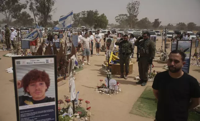 People stand still to observe two minutes of silence as air raid sirens sound marking the Israel's annual Memorial Day at the site of Oct. 7, 2023 attack by Hamas militants at the Nova music festival near Kibbutz Reim, southern Israel, Wednesday, April 30, 2025. (AP Photo/Ohad Zwigenberg)