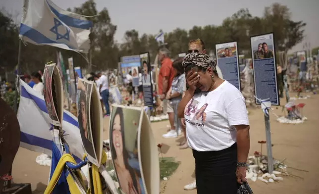 People stand still to observe two minutes of silence as air raid sirens sound marking the Israel's annual Memorial Day at the site of Oct. 7, 2023 attack by Hamas militants at the Nova music festival near Kibbutz Reim, southern Israel, Wednesday, April 30, 2025. (AP Photo/Ohad Zwigenberg)