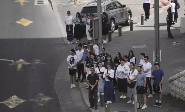 People stand still to observe two minutes of silence as air raid sirens sound marking the Israel's annual Memorial Day for the fallen soldiers and victims of nationalistic attacks in Jerusalem, Wednesday, April 30, 2025. (AP Photo/Mahmoud Illean)