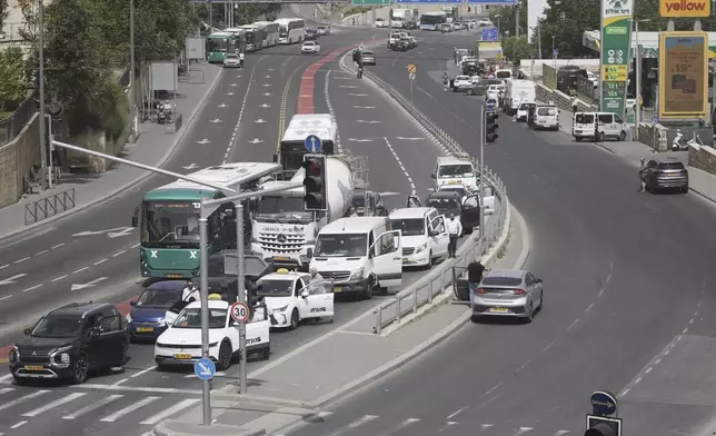 People stand still by their cars to observe two minutes of silence as air raid sirens sound marking the Israel's annual Memorial Day for the fallen soldiers and victims of nationalistic attacks in Jerusalem, Wednesday, April 30, 2025. (AP Photo/Mahmoud Illean)