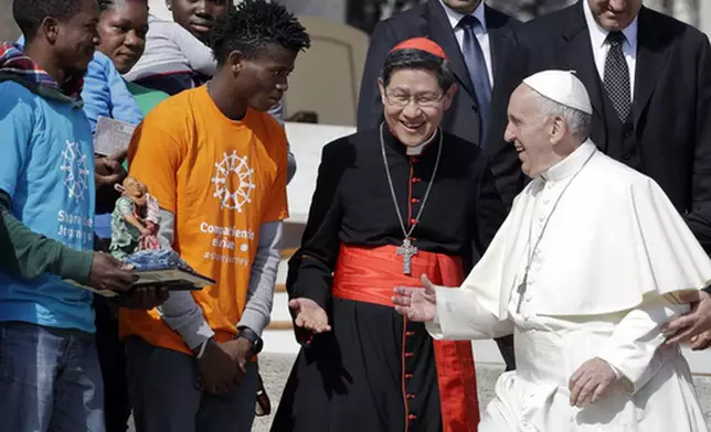 FILE - Pope Francis greets Cardinal Luis Antonio Tagle, archbishop of Manila, second from right, and group of migrants, during his weekly general audience, at the Vatican, Wednesday, Sept. 27, 2017. (AP Photo/Andrew Medichini, File)