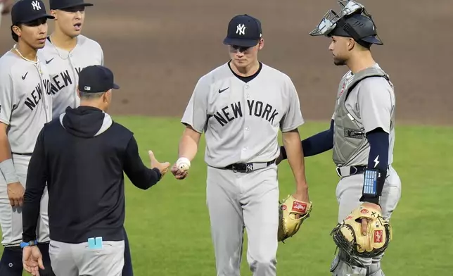 New York Yankees pitcher Will Warren, second from right, hands the ball to manager Aaron Boone as he is taken out of the game against the Tampa Bay Rays during the second inning of a baseball game Thursday, April 17, 2025, in Tampa, Fla. (AP Photo/Chris O'Meara)