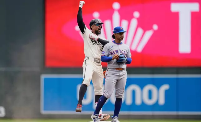 Minnesota Twins' Byron Buxton (25), left, celebrates next to New York Mets shortstop Francisco Lindor (12) after hitting an RBI-single during the fifth inning of a baseball game, Wednesday, April 16, 2025, in Minneapolis. (AP Photo/Abbie Parr)