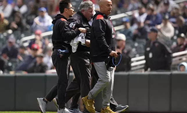 First base umpire Hunter Wendelstedt, center, walks off the field with medical staff after being hit by a foul ball during the seventh inning of a baseball game between the Minnesota Twins and New York Mets, Wednesday, April 16, 2025, in Minneapolis. (AP Photo/Abbie Parr)