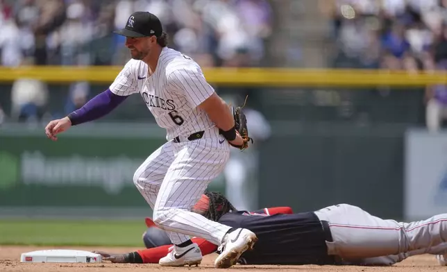 Colorado Rockies shortstop Kyle Farmer, front, reacts after tagging out Washington Nationals' Josh Bell while trying to steal second base in the fifth inning of Game 1 of a split baseball doubleheader Sunday, April 20, 2025, in Denver. (AP Photo/David Zalubowski)