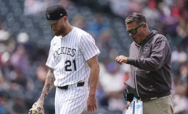 Colorado Rockies starting pitcher Kyle Freeland, left, heads to the dugout with trainer Keith Dugger as Freeland is pulled from the mound in the third inning of Game 1 of a split baseball doubleheader against the Washington Nationals, Sunday, April 20, 2025, in Denver. (AP Photo/David Zalubowski)