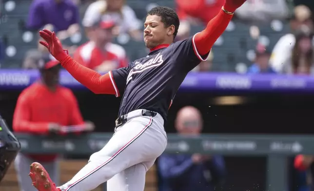 Washington Nationals' Trey Lipscomb slides safely into home plate to score on a throwing error by Colorado Rockies catcher Braxton Fulford in the second inning of Game 1 of a split baseball doubleheader Sunday, April 20, 2025, in Denver. (AP Photo/David Zalubowski)