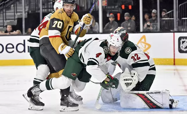 Minnesota Wild defenseman Jon Merrill (4) and goaltender Filip Gustavsson (32) defend the net against Vegas Golden Knights left wing Tanner Pearson (70) during the second period of Game 5 of a first-round NHL hockey playoff series Tuesday, April 29, 2025, in Las Vegas. (AP Photo/David Becker)