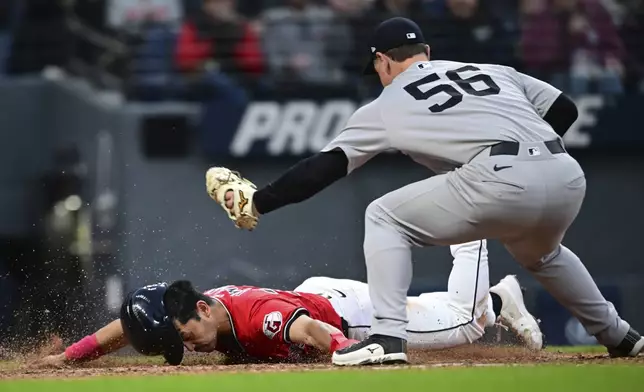 Cleveland Guardians' Steven Kwan slides to score a run on a pass ball by New York Yankees relief pitcher Mark Leiter Jr. during the sixth inning of a baseball game, Tuesday, April 22, 2025, in Cleveland. (AP Photo/David Dermer)