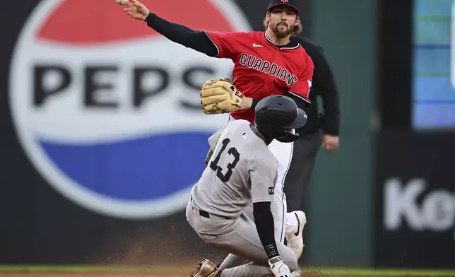Cleveland Guardians second baseman Daniel Schneemann, top, throws to first base after forcing out New York Yankees' Jazz Chisholm Jr. at second base during the fourth inning of a baseball game, Tuesday, April 22, 2025, in Cleveland. Anthony Volpe was out at first base for the double play. (AP Photo/David Dermer)