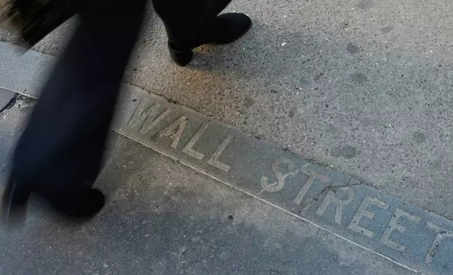 Pedestrians walk past a Wall Street sign on the sidewalk near the New York Stock Exchange in New York, Wednesday, April 9, 2025. (AP Photo/Seth Wenig)