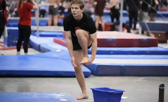 Brody Penn of Ohio State Club Gymnastics team puts chalk on his feet before warming up on the balance beam at the 2025 NAIGC national competition in Pittsburgh, Friday, April 4, 2025. (AP Photo/Gene J. Puskar)