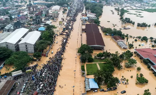 People walk through the flooded streets of Kinshasa, Democratic Republic of Congo Sunday, April 6, 2025. (AP Photo/Samy Ntumba Shambuyi)