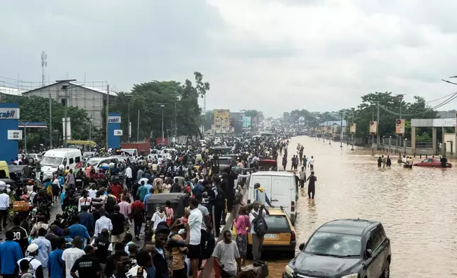 People walk through the flooded streets of Kinshasa, Democratic Republic of Congo Sunday, April 6, 2025. (AP Photo/Samy Ntumba Shambuyi)