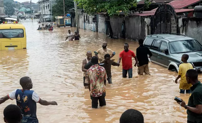People walk through the flooded streets of Kinshasa, Democratic Republic of Congo Sunday, April 6, 2025. (AP Photo/Samy Ntumba Shambuyi)