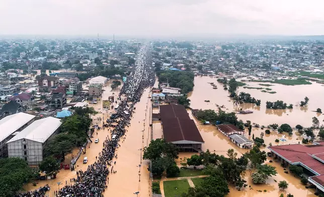 People walk through the flooded streets of Kinshasa, Democratic Republic of Congo Sunday, April 6, 2025. (AP Photo/Samy Ntumba Shambuyi)