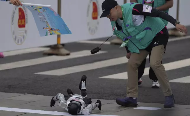 The crew of a robot reacts as the robot loses control at the start during the Humanoid Robot Half-Marathon held in Beijing on Saturday, April 19, 2025. (AP Photo/Ng Han Guan)