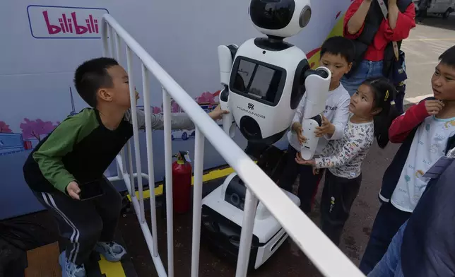 Children react to a wheeled robot after the Humanoid Robot Half-Marathon held in Beijing on Saturday, April 19, 2025. (AP Photo/Ng Han Guan)