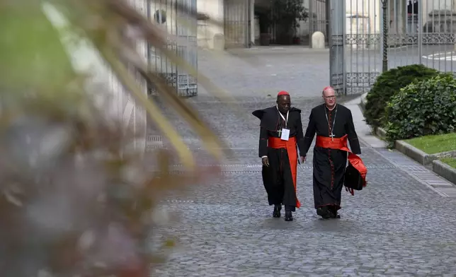 Cardinals Dieudonné Nzapalainga, left, and Timothy M. Dolan arrive for the Congregation of Cardinals in the New Hall of the Synod at the Vatican, Monday, April 28, 2025. (Vatican Media via AP)