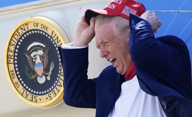 President Donald Trump holds his hat in the wind as he arrives on Air Force One at Selfridge Air National Guard Base, Tuesday, April 29, 2025, in Harrison Township, Mich. (AP Photo/Alex Brandon)
