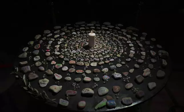 Stones painted with messages, olive leaves, and flowers surround a candle as a mandala of memory and hope at the 20th annual Israeli-Palestinian Memorial Day Ceremony in Jaffa, Israel, Tuesday, April 29, 2025. (AP Photo/Ariel Schalit)