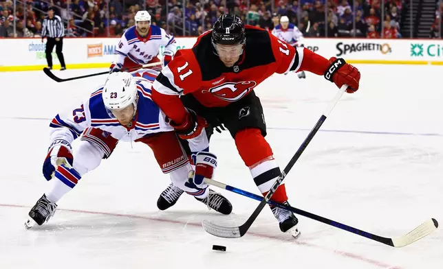 New York Rangers defenseman Adam Fox (23) and New Jersey Devils right wing Stefan Noesen (11) battle for the puck during the second period of an NHL hockey game, Saturday, April 5, 2025, in Newark, N.J. (AP Photo/Noah K. Murray)