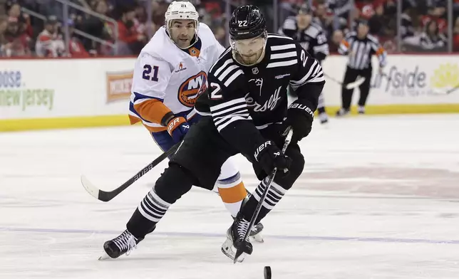 New Jersey Devils defenseman Brett Pesce (22) skates with the puck past New York Islanders center Kyle Palmieri in the third period of an NHL hockey game Sunday, April 13, 2025, in Newark, N.J. (AP Photo/Adam Hunger)