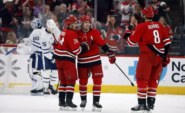 Carolina Hurricanes' Sebastian Aho, center, celebrates his goal against the Toronto Maple Leafs with teammates Seth Jarvis (24) and Brent Burns (8) during the third period of an NHL hockey game in Raleigh, N.C., Sunday, April 13, 2025. (AP Photo/Karl DeBlaker)