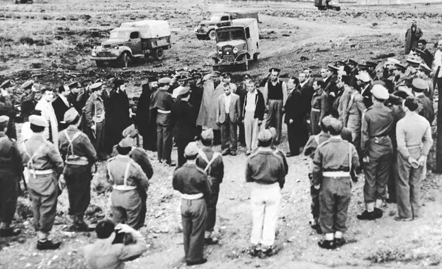 FILE - An officer reads execution orders to four condemned youths at a military installation near Athens, Greece, Oct. 29, 1947, as members of a firing squad stand with their backs to the camera. The youths, all from Peristeri, an Athens suburb, were convicted of aiding a Communist rebellion, conspiracy and a slaying. (AP Photo, File)