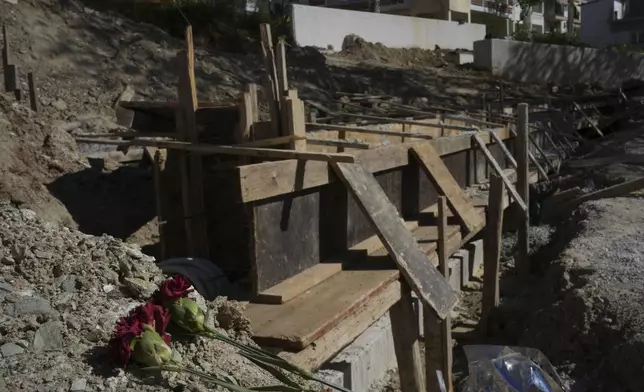Flowers lie at the site where mass graves containing remains believed to have belonged to dozens of prisoners executed during or after the Greek Civil War were uncovered in Thessaloniki, Greece, Friday, April 11, 2025. (AP Photo/Thanassis Stavrakis)