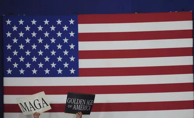 Supporters hold signs as President Donald Trump speaks on his first 100 days at Macomb County Community College Sports Expo Center, Tuesday, April 29, 2025, in Warren, Mich. (AP Photo/Paul Sancya)