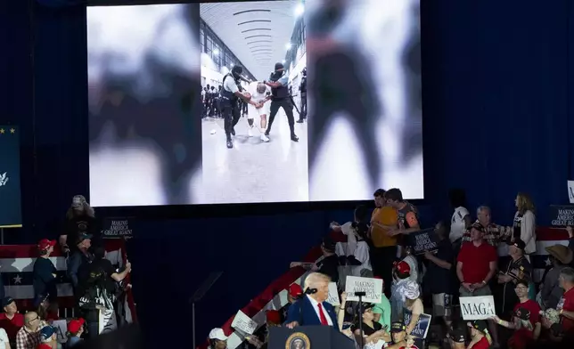 President Donald Trump shows a video on detainees in El Salvador as he speaks on his first 100 days at Macomb County Community College Sports Expo Center, Tuesday, April 29, 2025, in Warren, Mich. (AP Photo/Alex Brandon)