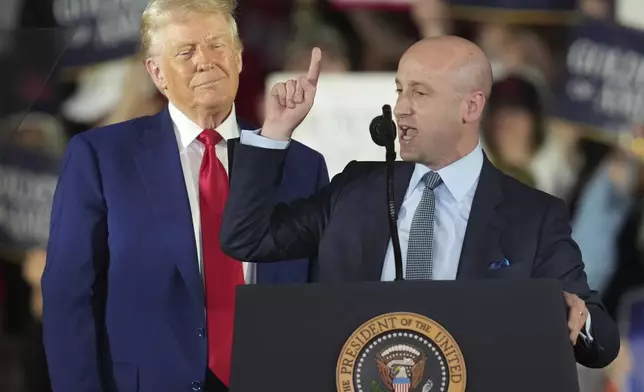 President Donald Trump listens as White House deputy chief of staff for policy Stephen Miller speaks on his first 100 days at Macomb County Community College Sports Expo Center, Tuesday, April 29, 2025, in Warren, Mich. (AP Photo/Paul Sancya)