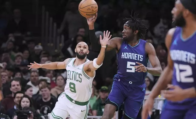 Boston Celtics guard Derrick White (9) tries to steal the ball from Charlotte Hornets center Mark Williams (5) during the first half of an NBA basketball game, Friday, April 11, 2025, in Boston. (AP Photo/Charles Krupa)