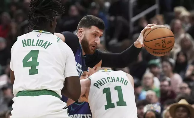Charlotte Hornets center Jusuf Nurkic, center, gets trapped by Boston Celtics' Jrue Holiday (4) and Payton Pritchard (11) during the first half of an NBA basketball game, Friday, April 11, 2025, in Boston. (AP Photo/Charles Krupa)