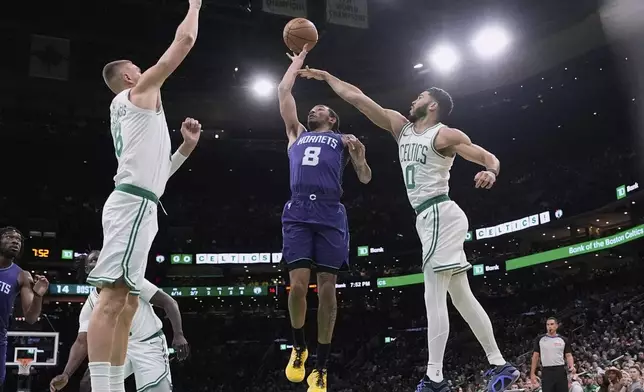 Charlotte Hornets guard Nick Smith Jr. (8) drives to the basket past Boston Celtics forward Jayson Tatum (0) and center Kristaps Porzingis (8) during the first half of an NBA basketball game, Friday, April 11, 2025, in Boston. (AP Photo/Charles Krupa)