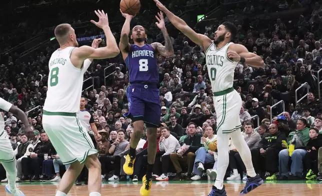 Charlotte Hornets guard Nick Smith Jr. (8) drives to the basket between Boston Celtics forward Jayson Tatum (0) and center Kristaps Porzingis (8) during the first half of an NBA basketball game, Friday, April 11, 2025, in Boston. (AP Photo/Charles Krupa)