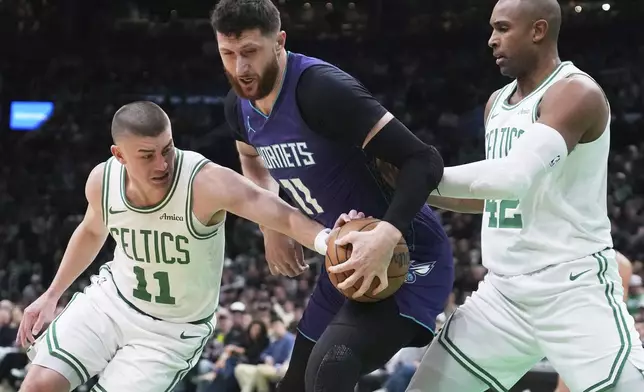 Boston Celtics guard Payton Pritchard, left, tries to steal the ball from Charlotte Hornets center Jusuf Nurkic, center, during the first half of an NBA basketball game, Friday, April 11, 2025, in Boston. (AP Photo/Charles Krupa)