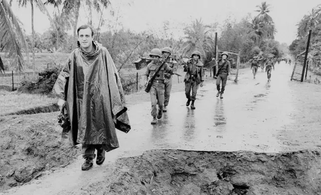 Associated Press correspondent Peter Arnett, left, marches in column with Vietnamese troops as he covers the war in Vietnam, Nov. 11, 1965. The conflict is described as one of the most difficult and dangerous for those who cover it because of the way it is fought. There are no front lines or clearly marked friendly or enemy territories. (AP Photo)