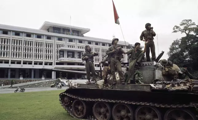 FILE- Victorious North Vietnamese troops aboard a tank take a position outside Independence Palace in Saigon, April 30, 1975, the day the South Vietnamese government surrendered, ending the Vietnam War. Communist flags fly from the palace and the tank. (AP Photo/Yves Billy, File)