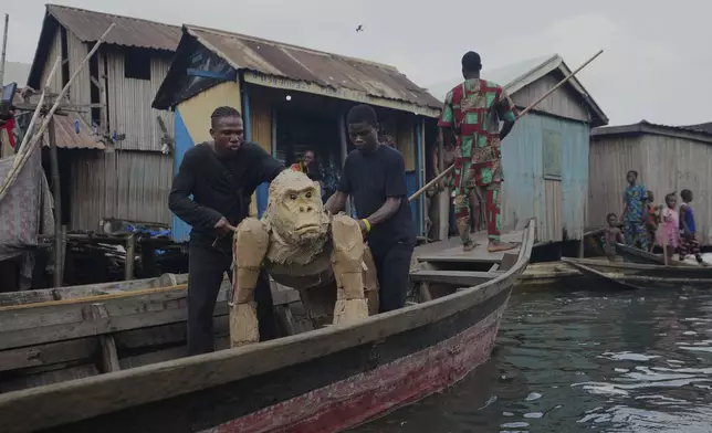 Puppeteers move cardboard animals in canoes at the Makoko Slum in Lagos Nigeria, Saturday, April 19, 2025, as part of "The Herds," a moving theatre performance that started its journey from the Democratic Republic of the Congo to the Arctic Circle in a bid to bring attention to the climate crisis. (AP Photo/Sunday Alamba)
